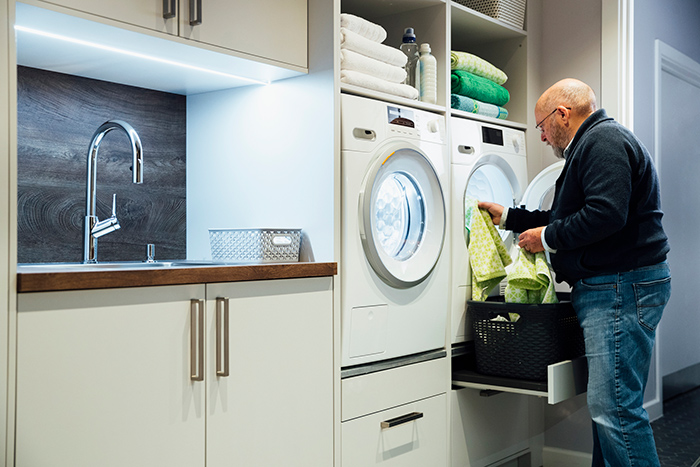 Senior man standing doing laundry taking clothes out of dryer