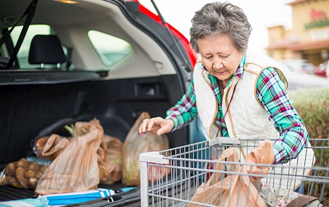 Senior woman loading the back of car with bagged groceries