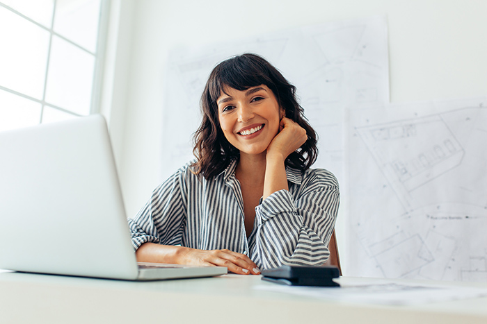 Smiling professional woman sitting behind open laptop