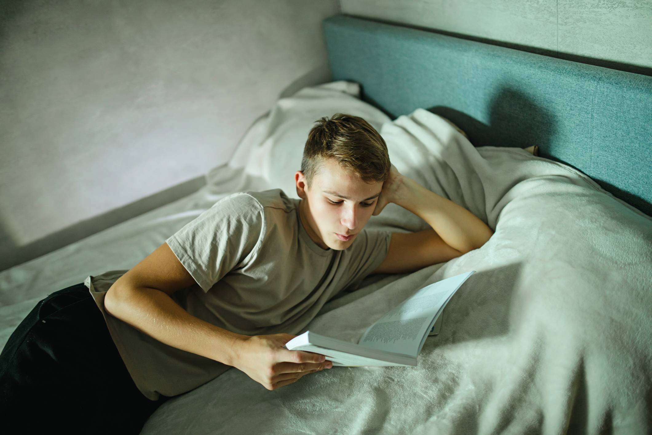 Teenager reading a book in bed