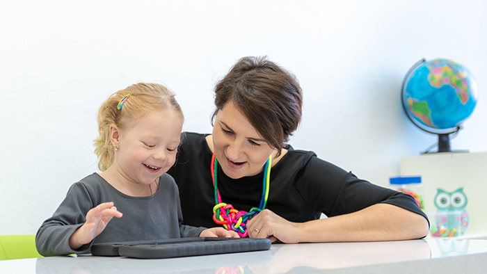 Woman working with tablet at desk with smiling toddler girl