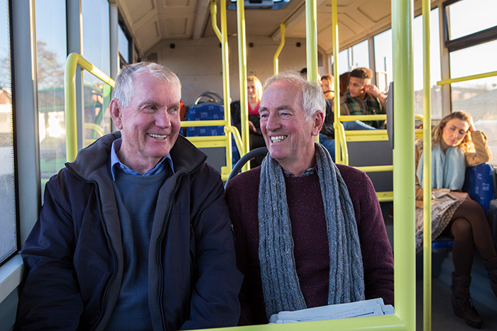 Two senior men sitting next to each other in public bus