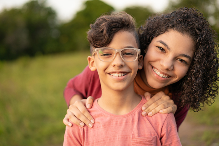 Two smiling young adults outside smiling at camera