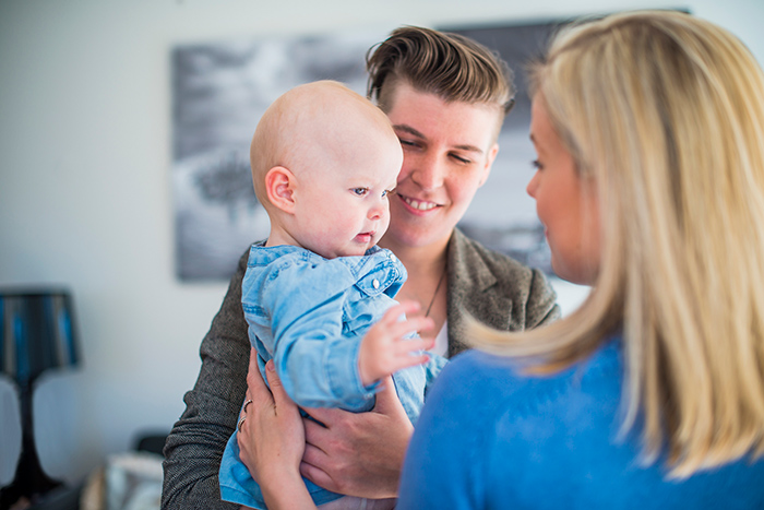 Two women holding infant baby at home