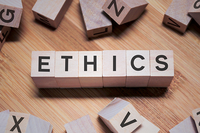 Wood blocks that spell the word ethics with others scattered on the table