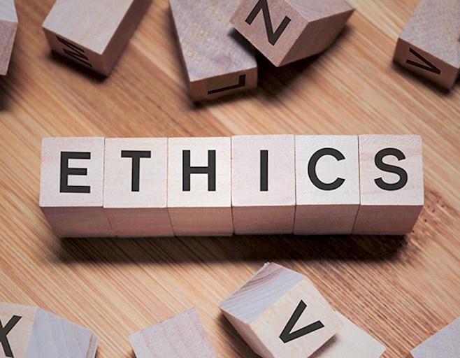Wood blocks that spell the word ethics with others scattered on the table