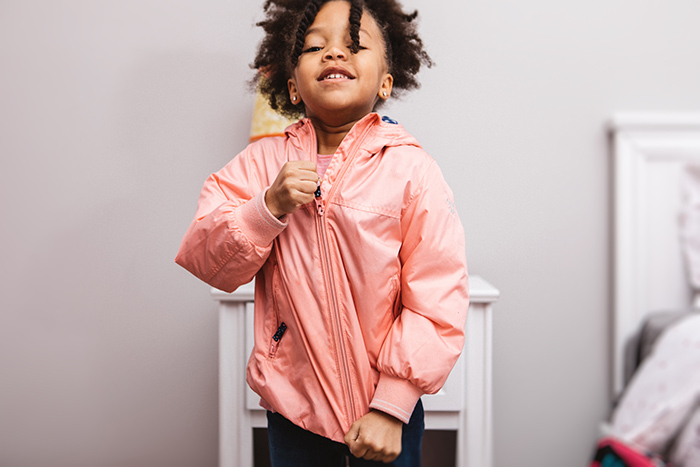 Young girl zipping up jacket