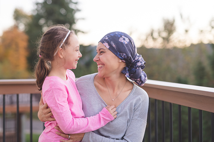 Woman wearing headscarf smiling and embracing young girl outside on deck