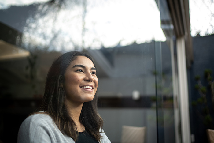 Young woman smiling and looking out through a window