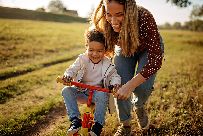 Woman outside with small child teaching him how to ride a bike