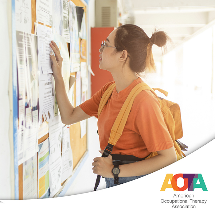 Young female wearing backpack looking at fliers on corkboard hung on the wall