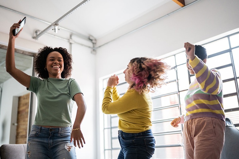 A group of three young people dancing and smiling