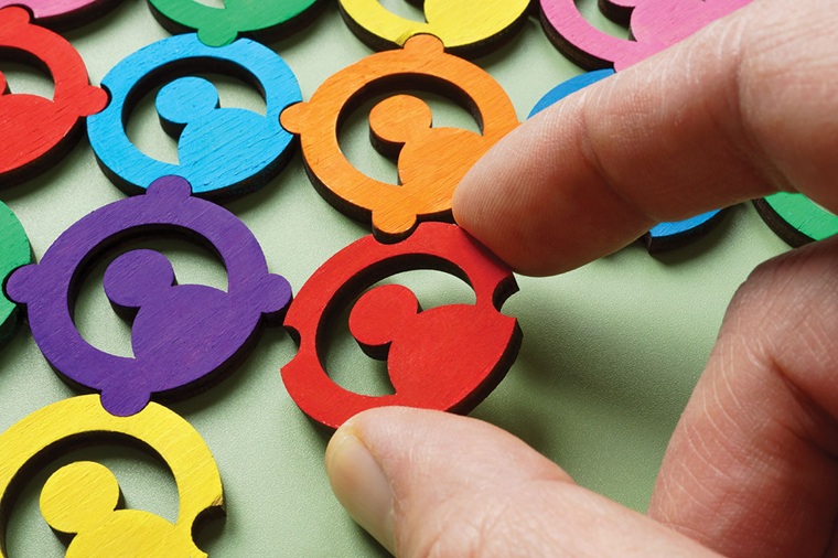 A hand placing colorful "people" puzzle pieces