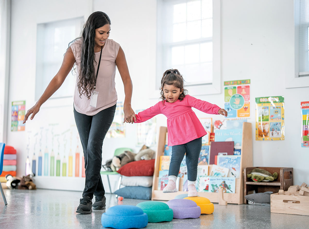 Teacher helping young girl with sensory activities in school setting