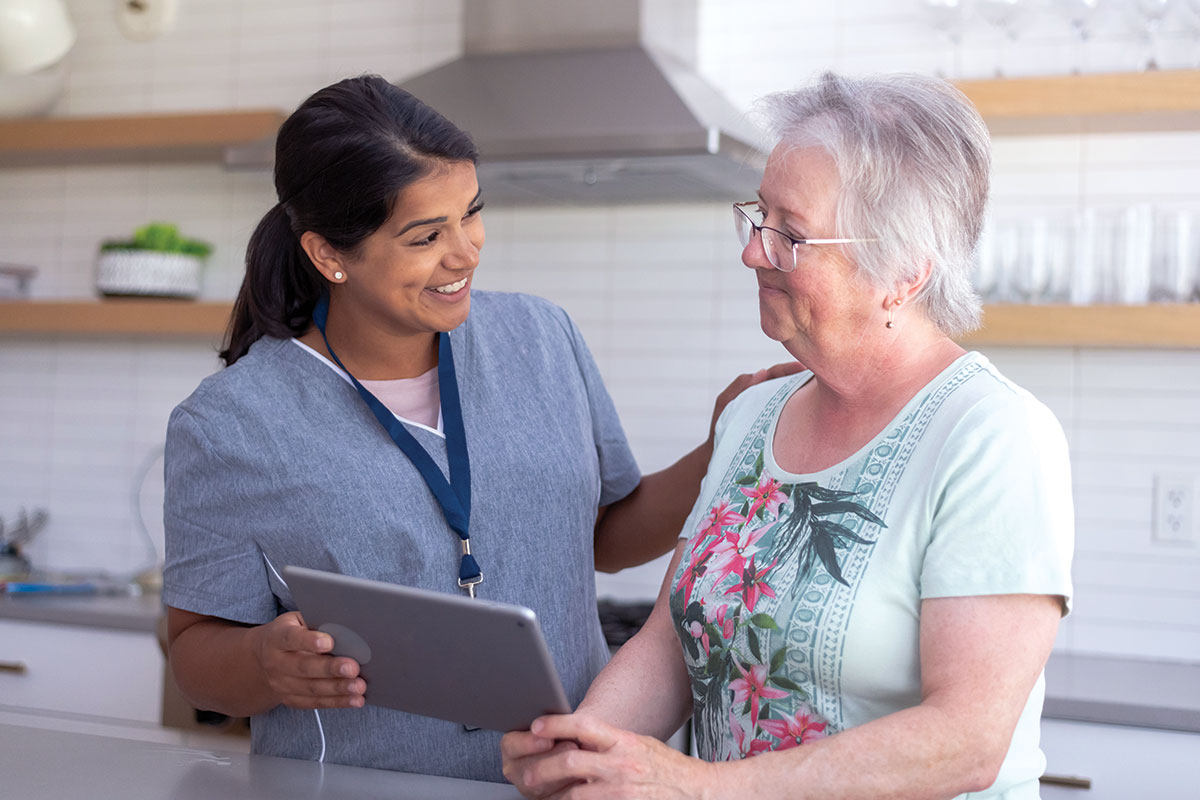 Younger woman with tablet, smiling, and sitting with an older woman
