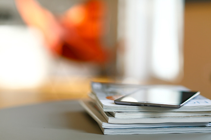 Stack of magazines on desk with eReader on top