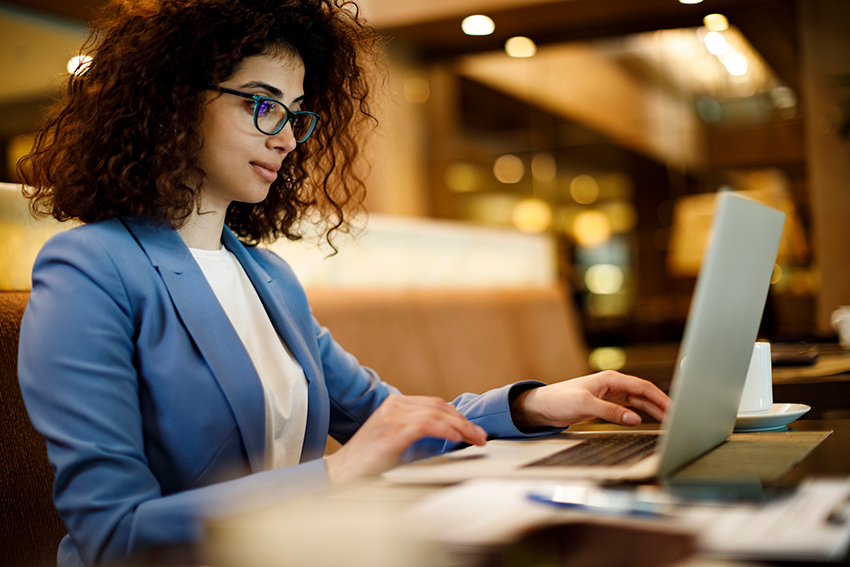 Professional woman sitting at table working on laptop