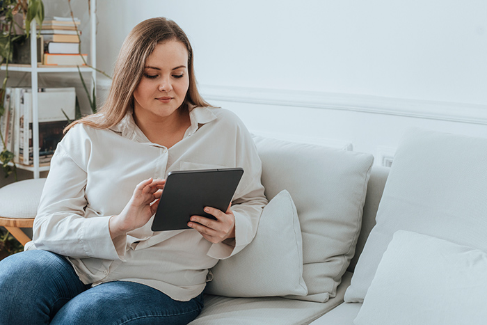 Woman sitting on couch reading tablet