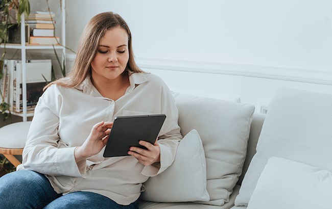 Woman sitting on couch reading tablet