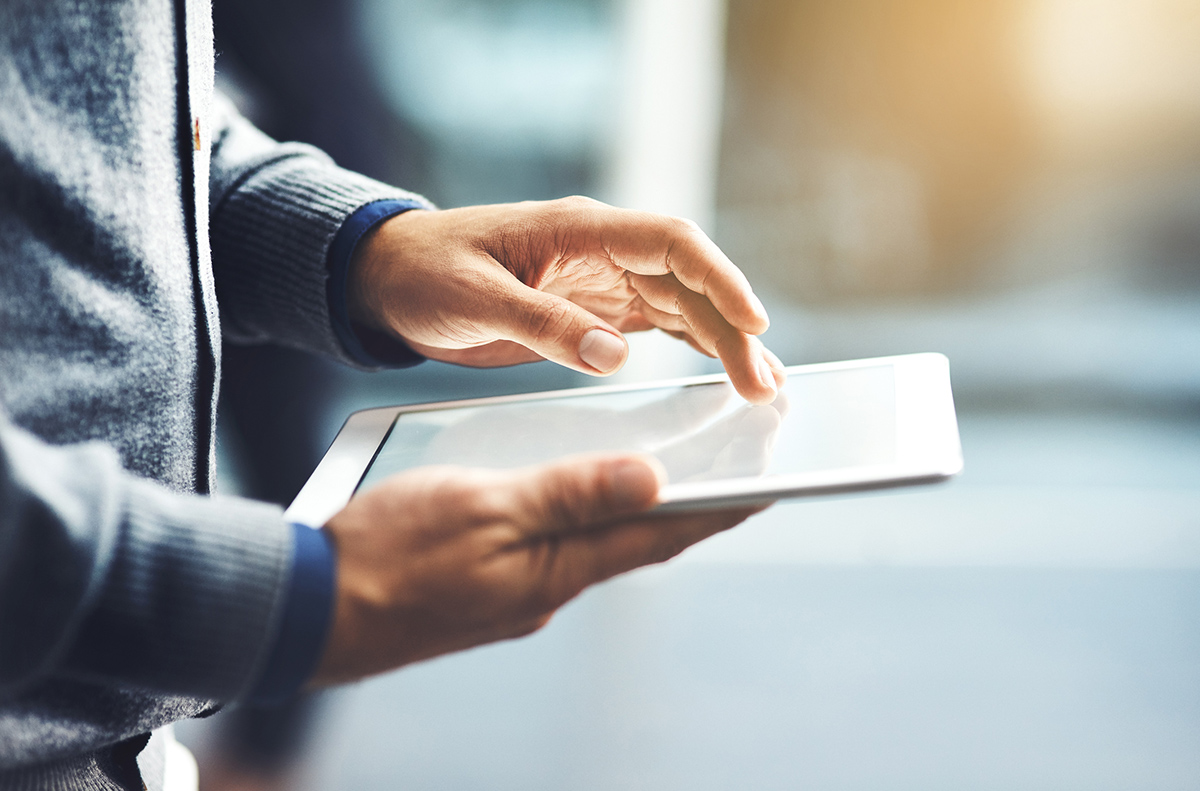 Close up of male hands using a tablet in front of a blurred background