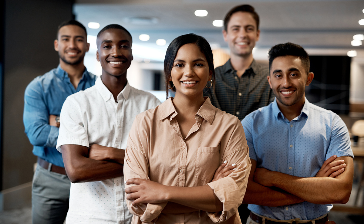Five diverse professionals with arms crossed posing for camera inside office
