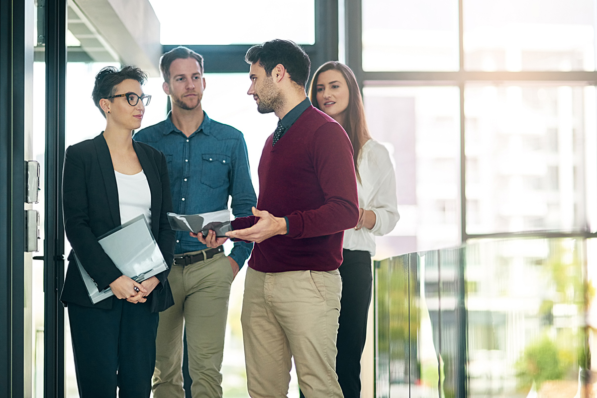 Two women and two men talking and walking through office for site visit