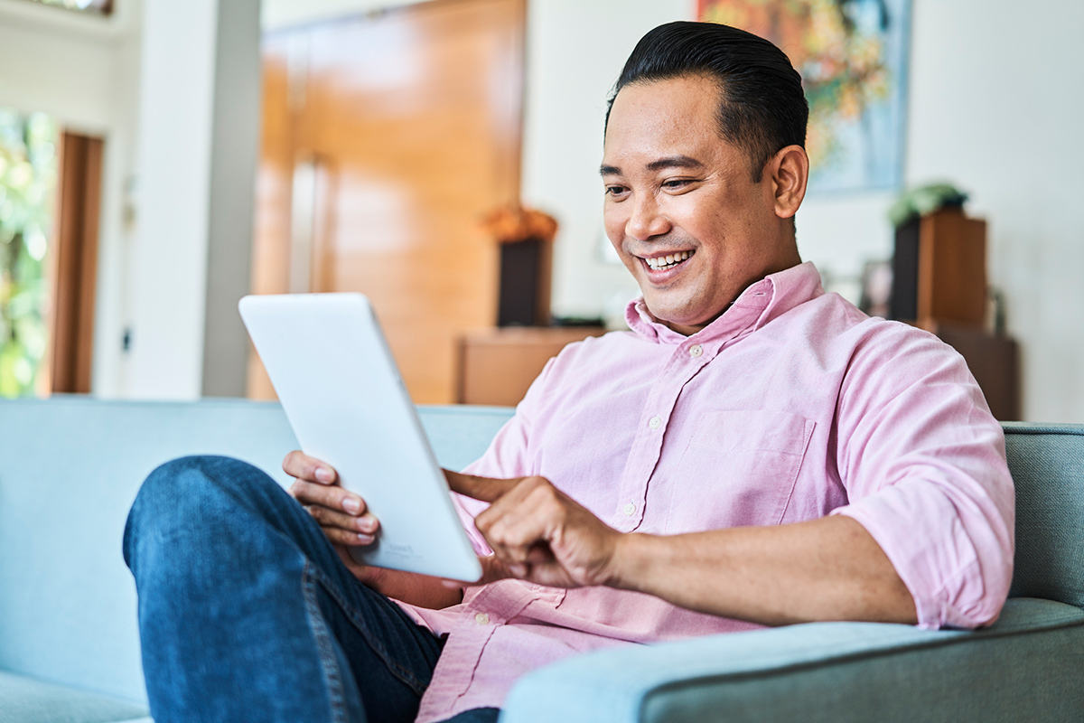 Man casually reading tablet at home on couch