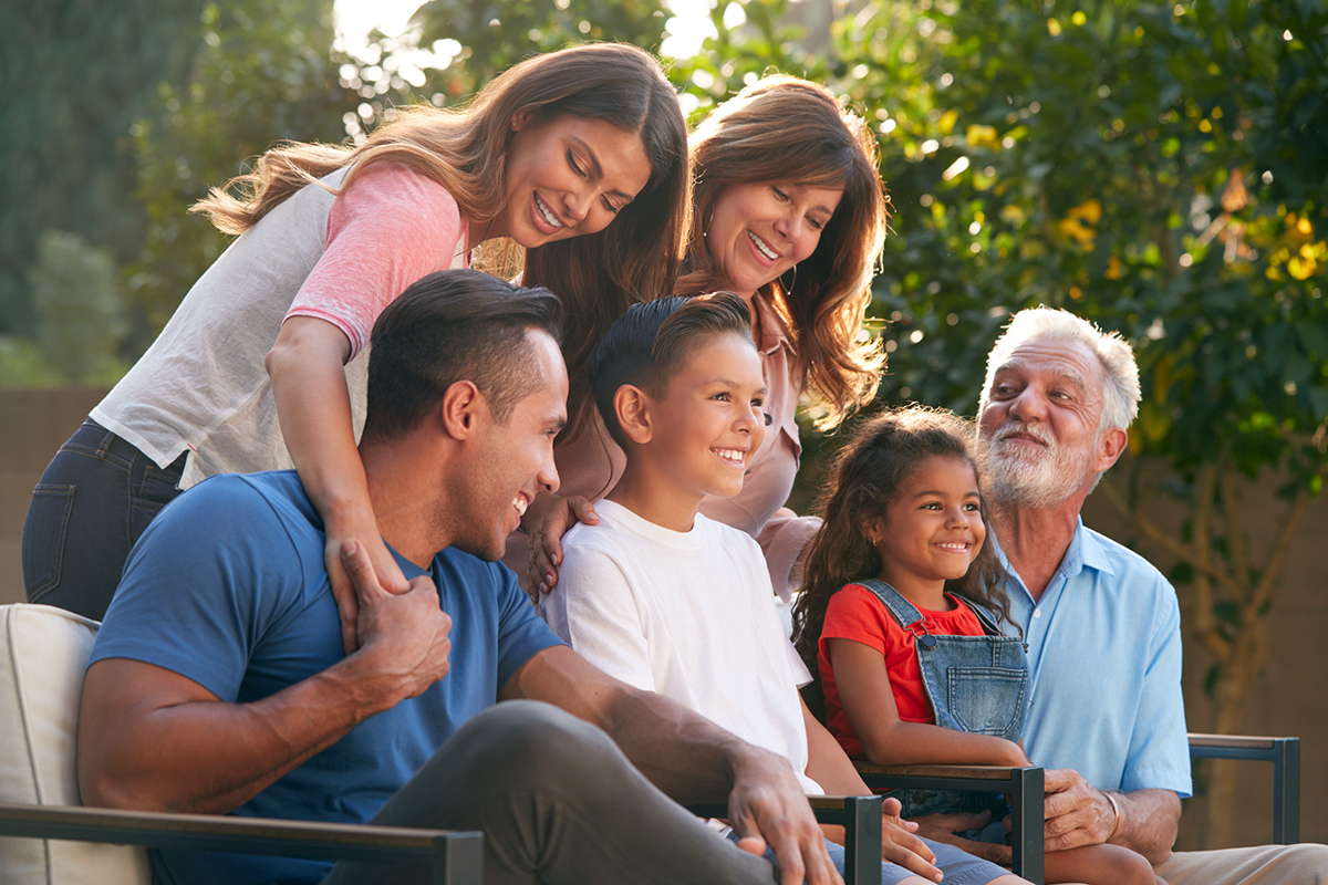 Multigenerational family posing outside on bench for a picture