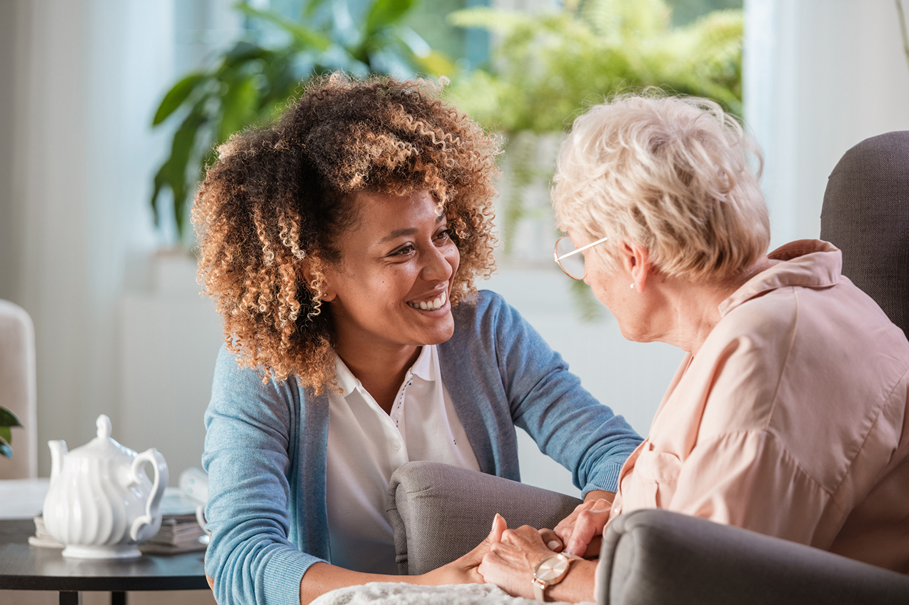 Female occupational therapist talking with elderly client and smiling