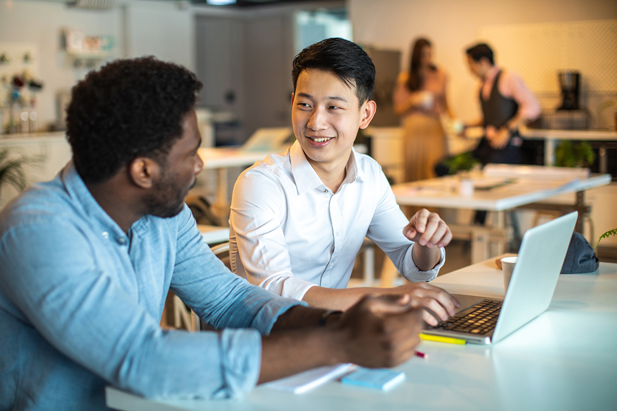Two men talking together working at a computer