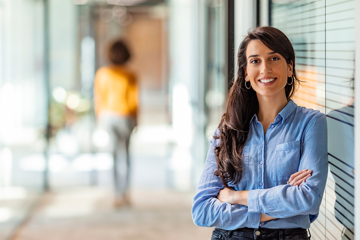 Woman crossing her arms smiling at camera inside an office building