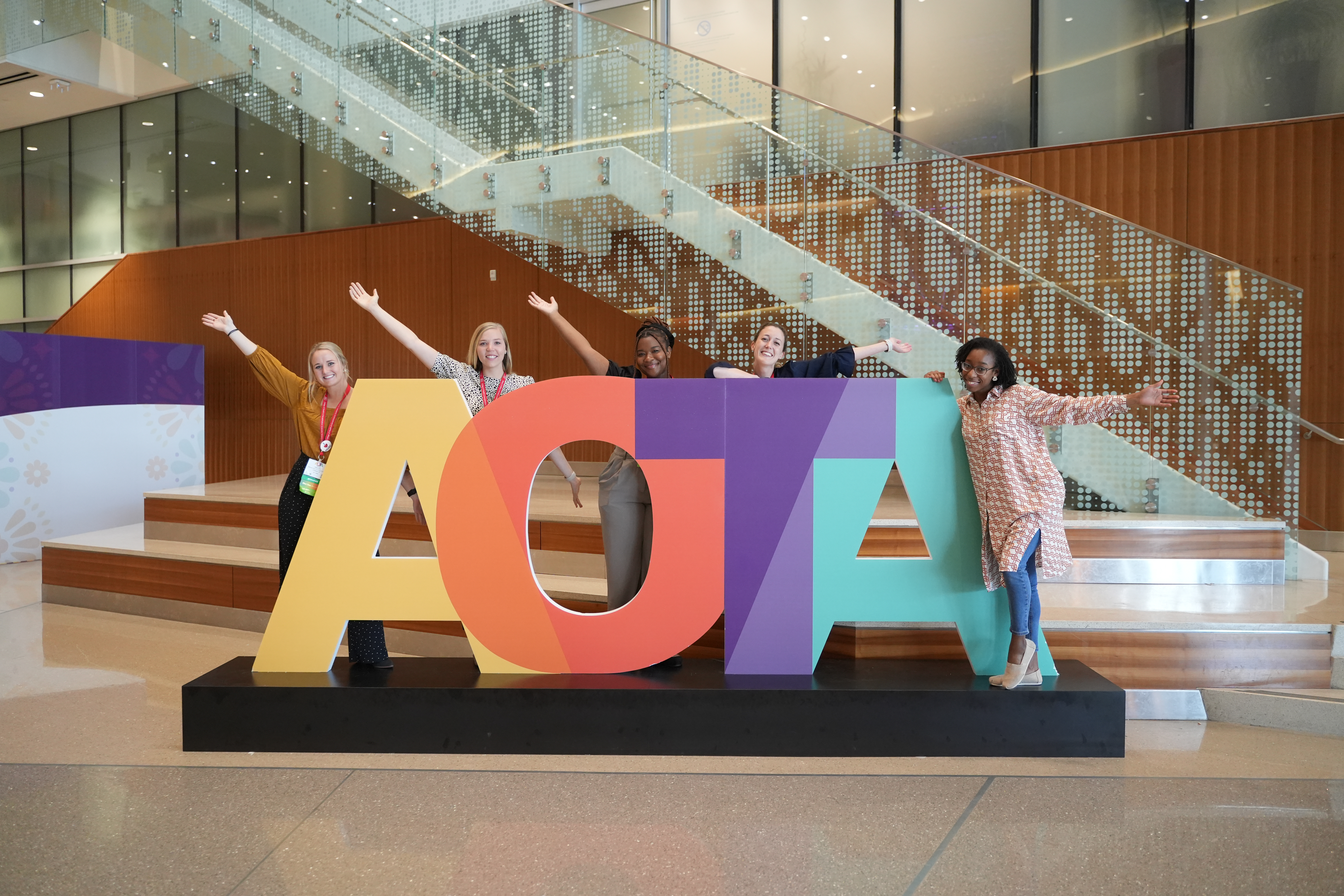 Four people standing behind the AOTA letters at annual conference