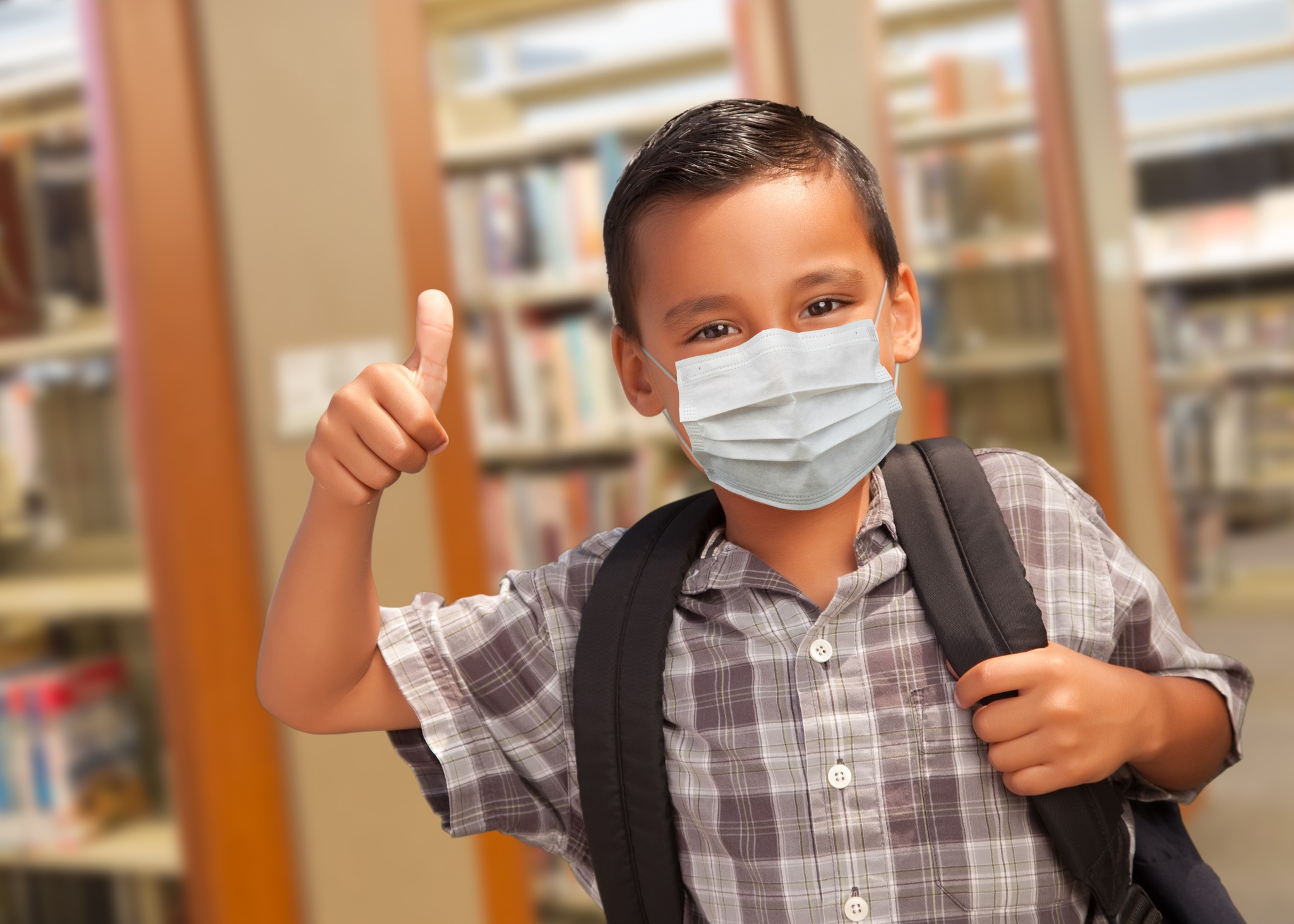 A boy going to school wearing a backpack and covid mask.