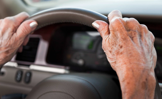 hands on a steering wheel while driving a car.