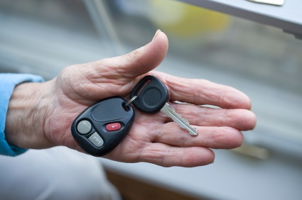 The hand of a elderly driver with car keys in the palm.