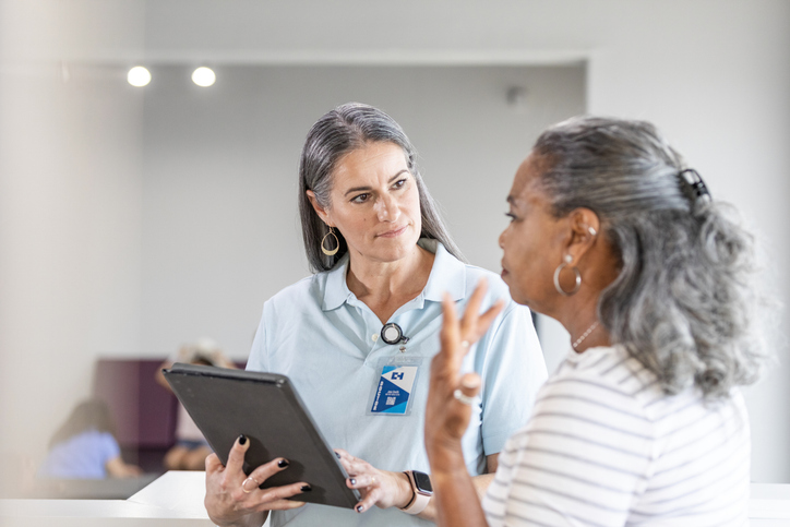 Patient talking to practitioner holding a clipboard
