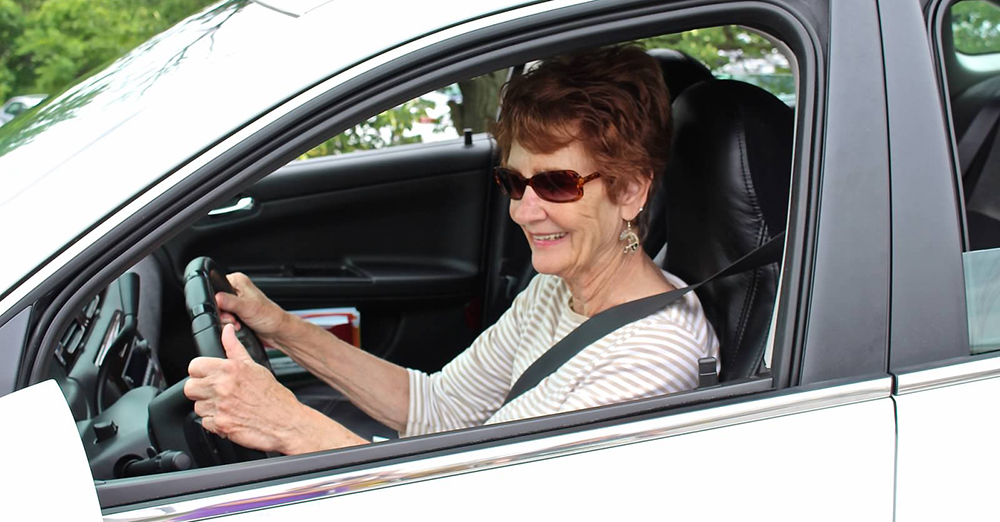 Female occupational therapist helping senior woman get out of bed and use walker