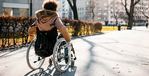  view of person in wheelchair in a park-like setting, moving away