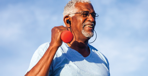 Man with sunglasses smiling and holding a red barbell