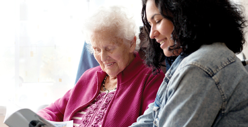Two people reading a magazine, one an older adult