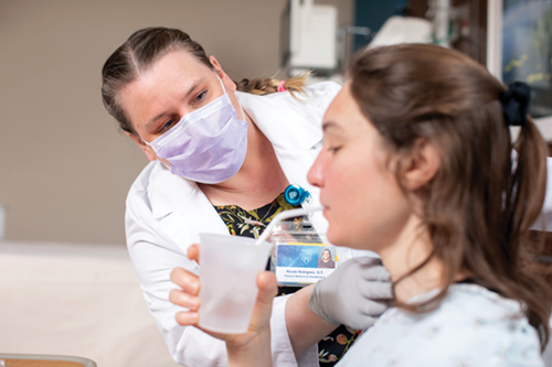 Occupational therapist palpates the neck to feel for laryngeal elevation during the swallow.