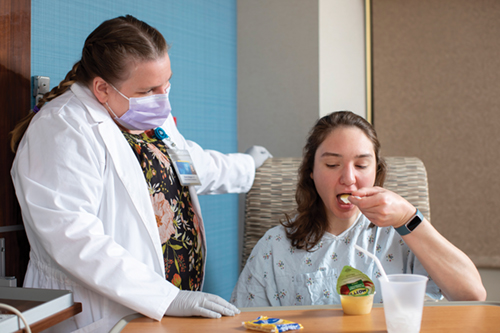 Occupational therapist evaluating patient eating applesauce during a tableside dysphagia assessment.