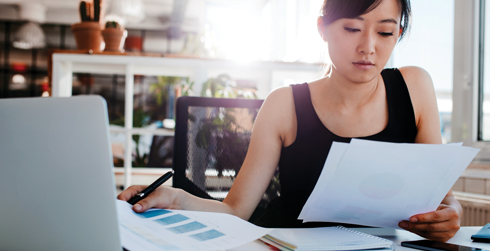 Woman looking over some paperwork at a desk.
