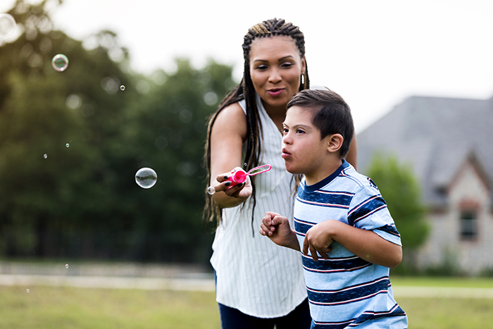 woman with child blowing bubbles outside developmental disability children and youth